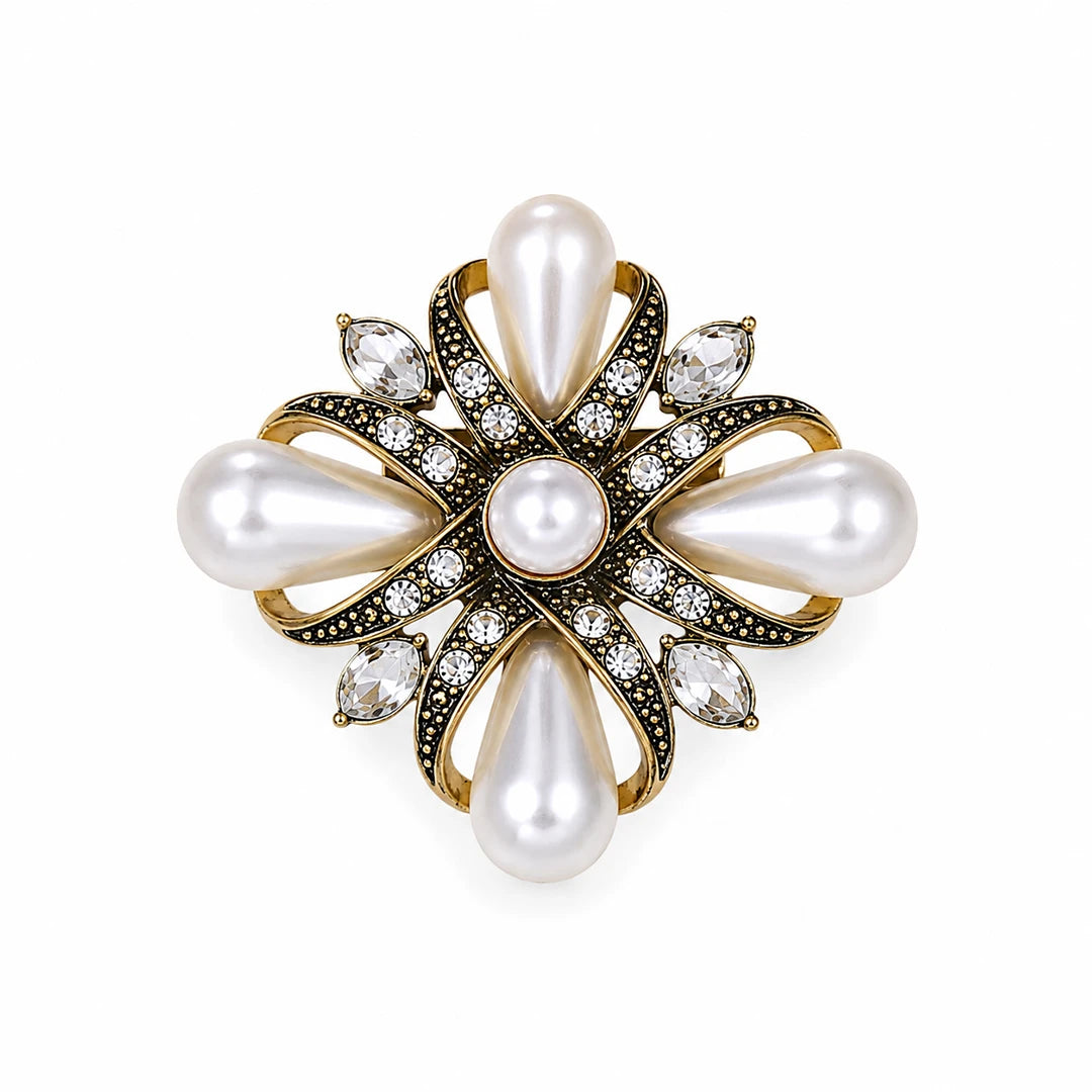 A vintage-style floral brooch featuring white pearls, gold-toned metal, and small clear crystals on a plain white background.