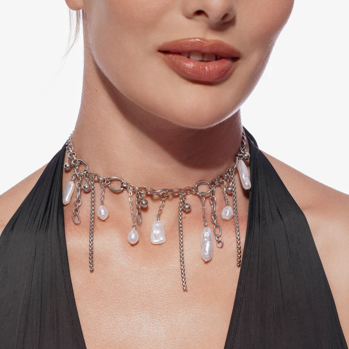 Model wearing a silver choker necklace with dangling baroque pearls and chain accents, close-up