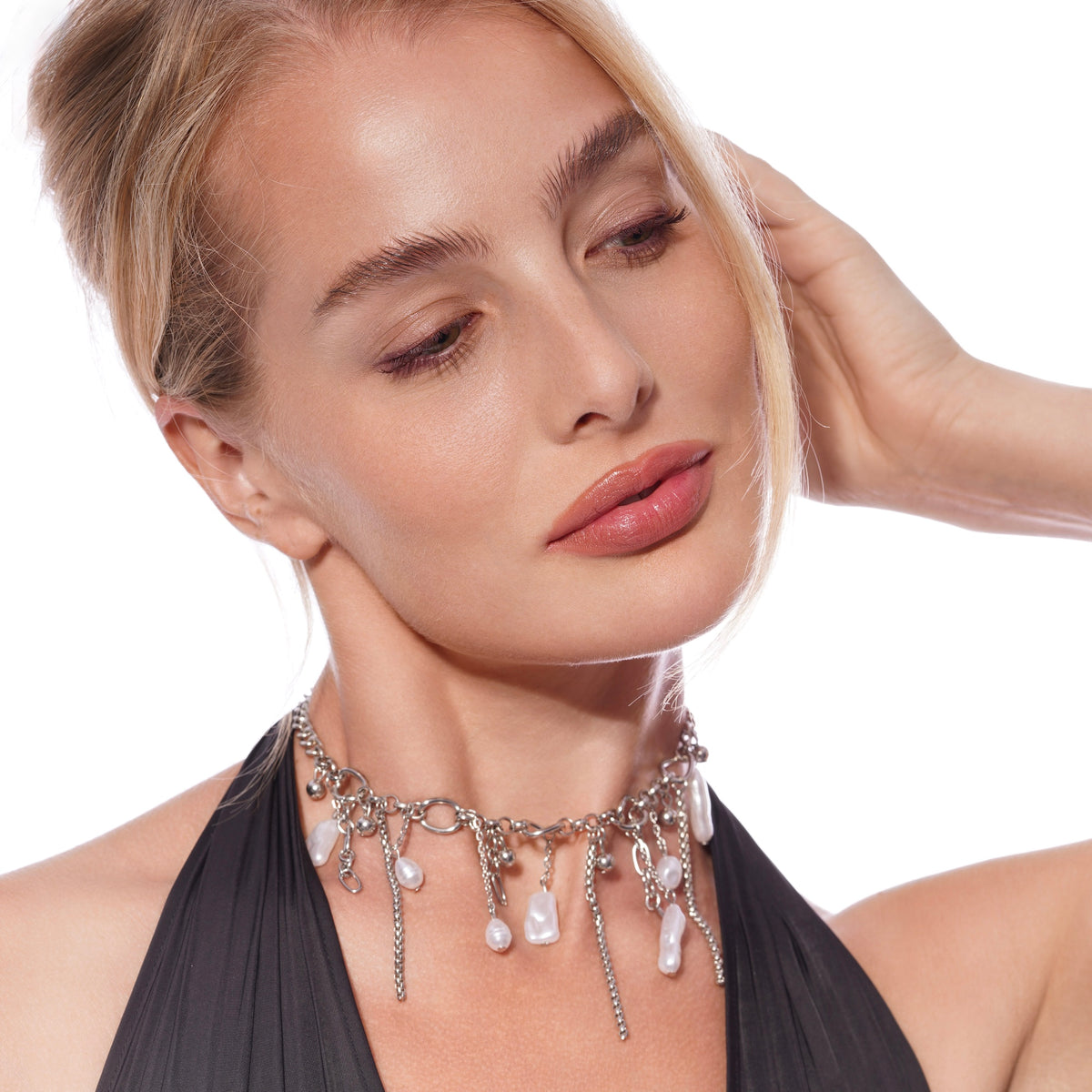 Woman wearing a silver choker necklace with dangling teardrop and oval pearl charms